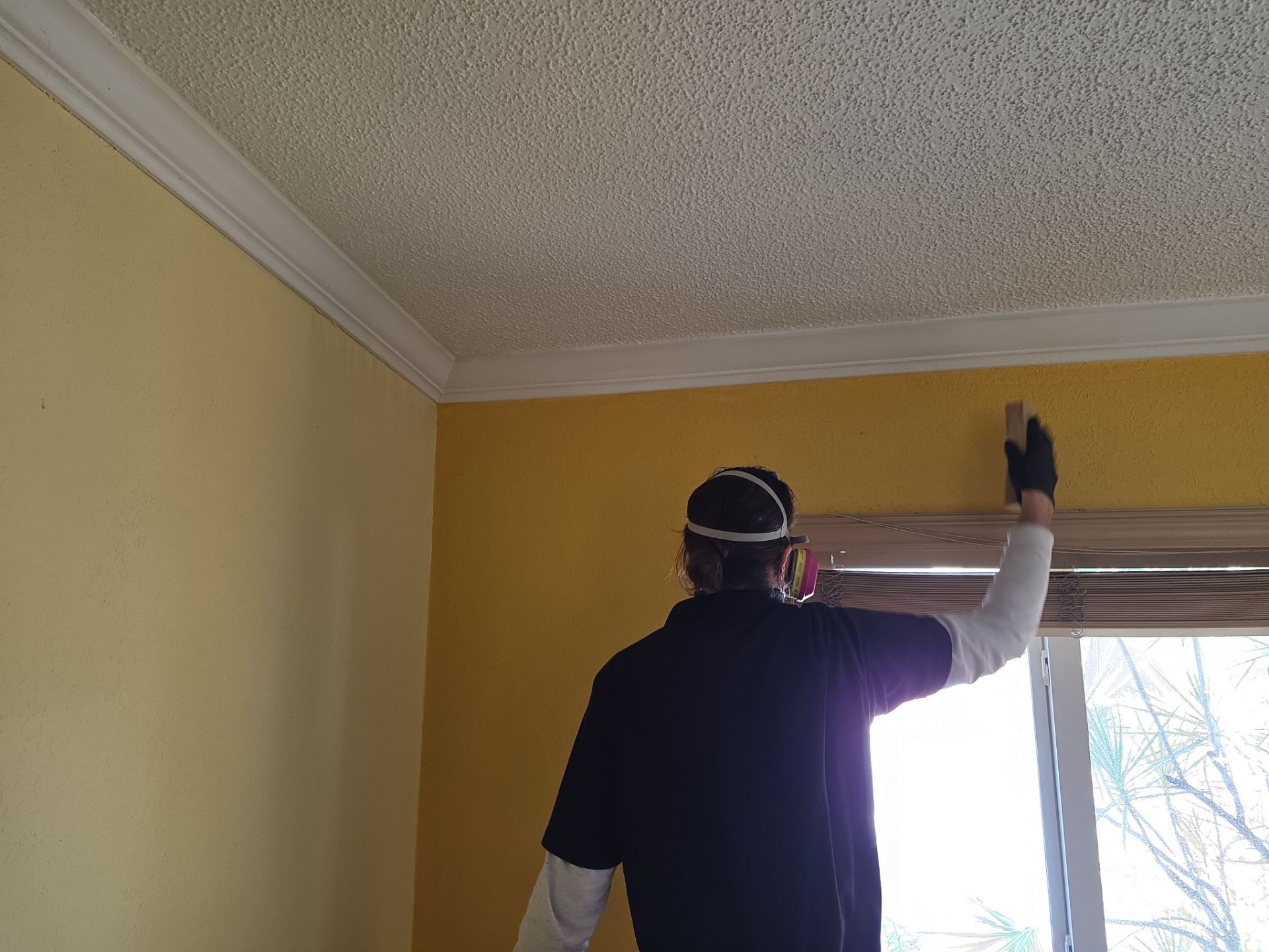 Technician scrubbing smoke residue from walls near ceiling